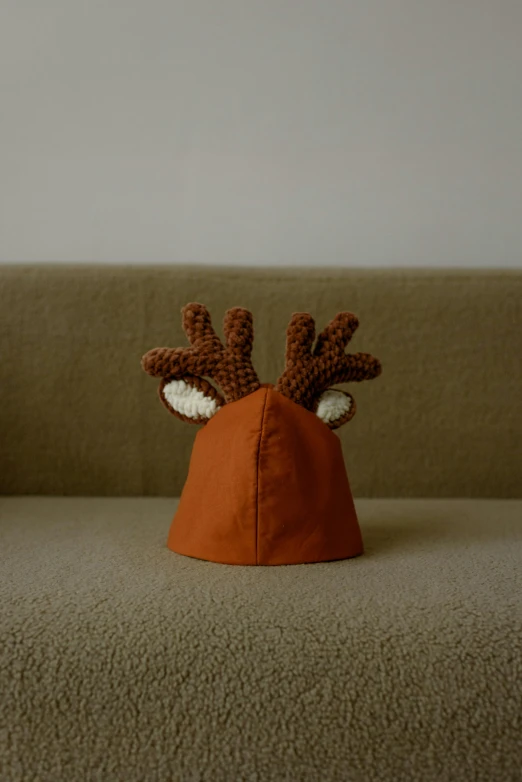 a close up of a stuffed animal on a couch, by Simon Gaon, unsplash, photorealism, horns on head, orange balaclava, in claymation, jeongseok lee