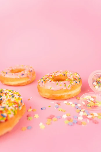 a number of doughnuts with sprinkles on a pink surface, by Julia Pishtar, holographic plastic, ((pink)), essence, 15081959 21121991 01012000 4k