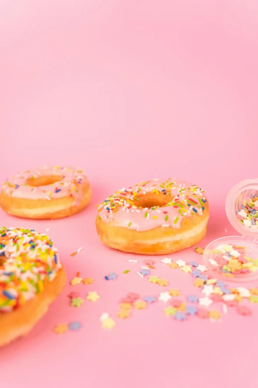 a number of doughnuts with sprinkles on a pink surface, by Julia Pishtar, holographic plastic, ((pink)), essence, 15081959 21121991 01012000 4k