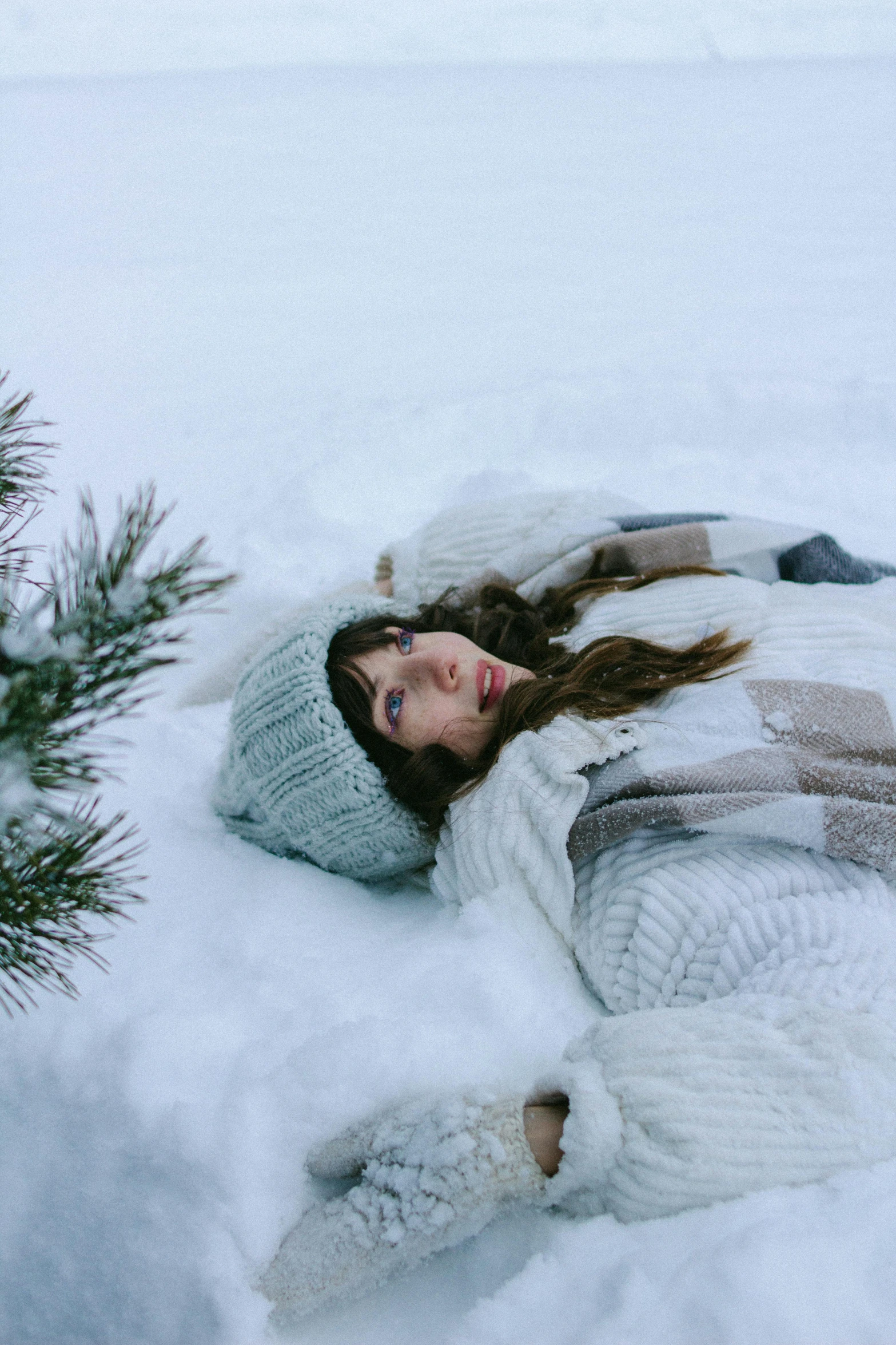 a woman laying in the snow next to a tree, pexels contest winner, symbolism, dafne keen, 8 k )