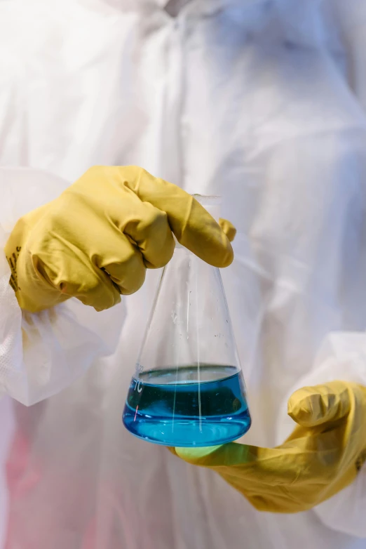 a person holding a flask filled with blue liquid, a picture, shutterstock, yellow latex gloves, sci-fiish, contain, just