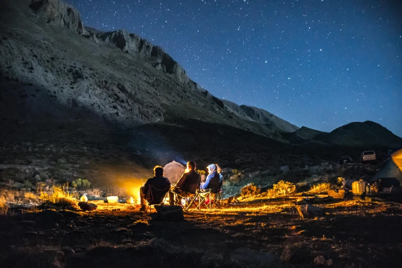 a group of people sitting around a campfire at night, pexels contest winner, les nabis, high in mountains, people on a picnic, geology, conde nast traveler photo