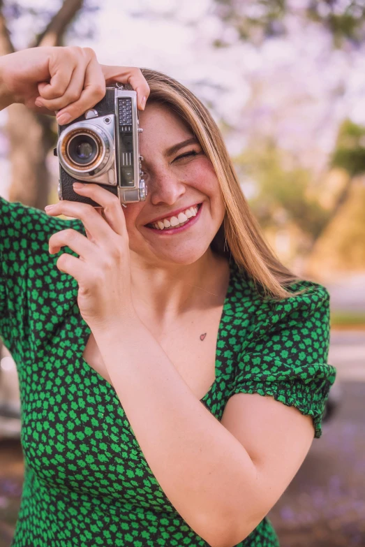 a woman taking a picture with a camera, smiling for the camera, sydney sweeney, in retro colors, zoomed in