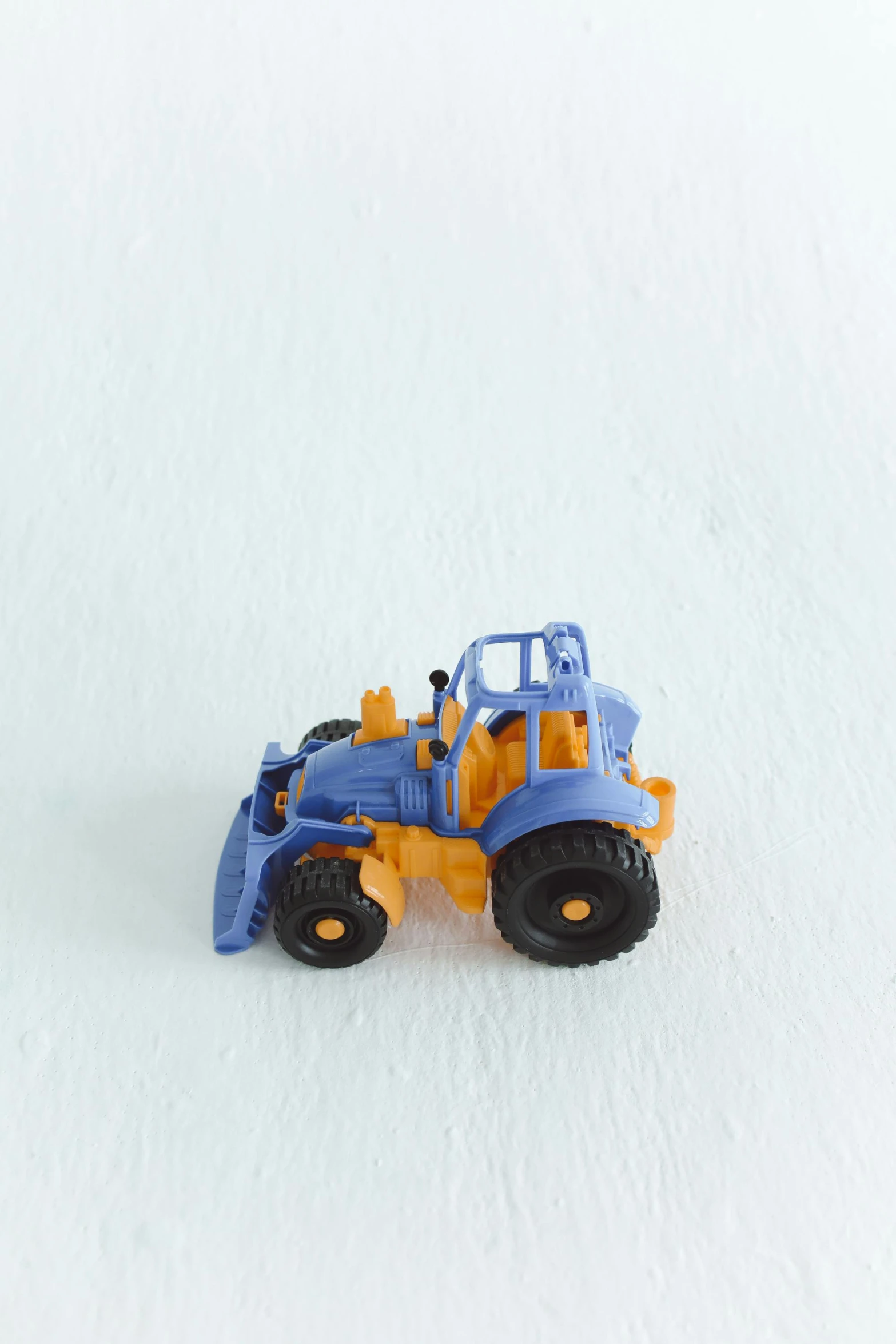 a close up of a toy tractor on a white surface, by Andries Stock, blue!! with orange details, environmental, 2 0 0 0 s, small