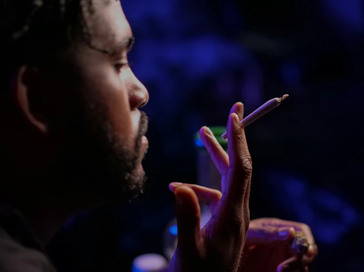 a man smoking a cigarette in a dark room, chief keef, profile image, ice cube, concert photo