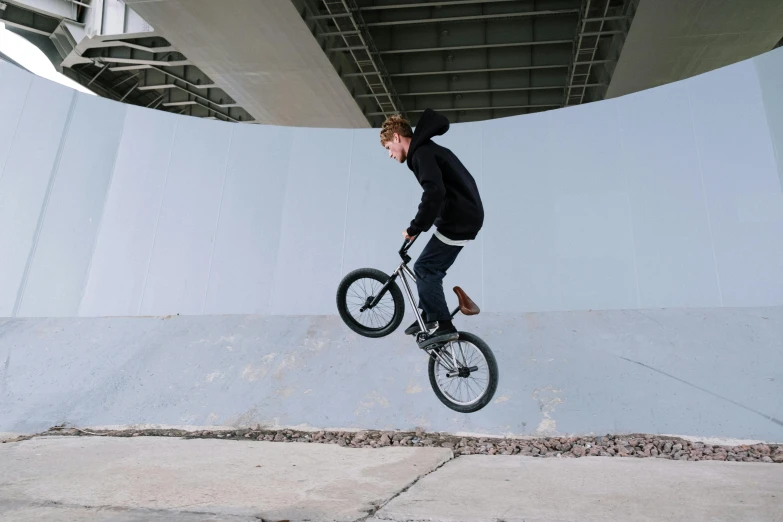 a man flying through the air while riding a bike, inspired by Seb McKinnon, pexels contest winner, realism, yung lean, overpass, bulky build, no extra ears