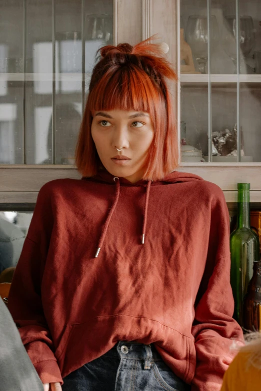 a woman sitting on top of a kitchen counter, inspired by Ruth Jên, trending on pexels, hyperrealism, red short hair, japanese streetwear, looking straight into camera, red clothes