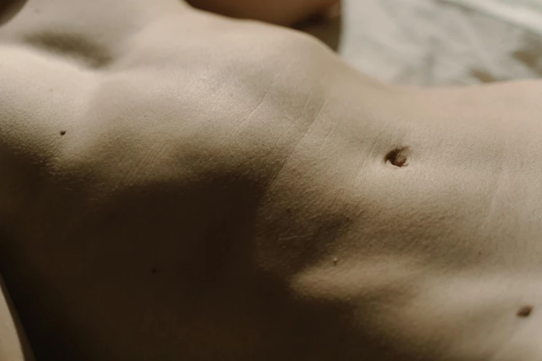 a close up of a person laying on a bed, by Elsa Bleda, trending on pexels, hyperrealism, abdominal muscles, pierced navel, graceful body structure, tans