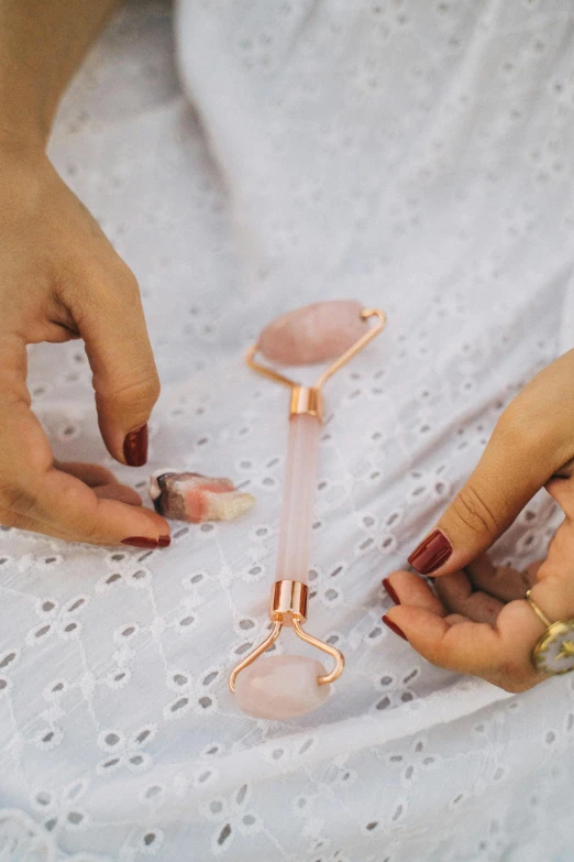 a woman in a white dress holding a rose quartz stone, instagram, tools, lying down, rose gold, hanging