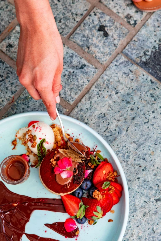 a person holding a spoon over a plate of food, desserts, in chippendale sydney, landscape vista, chocolate