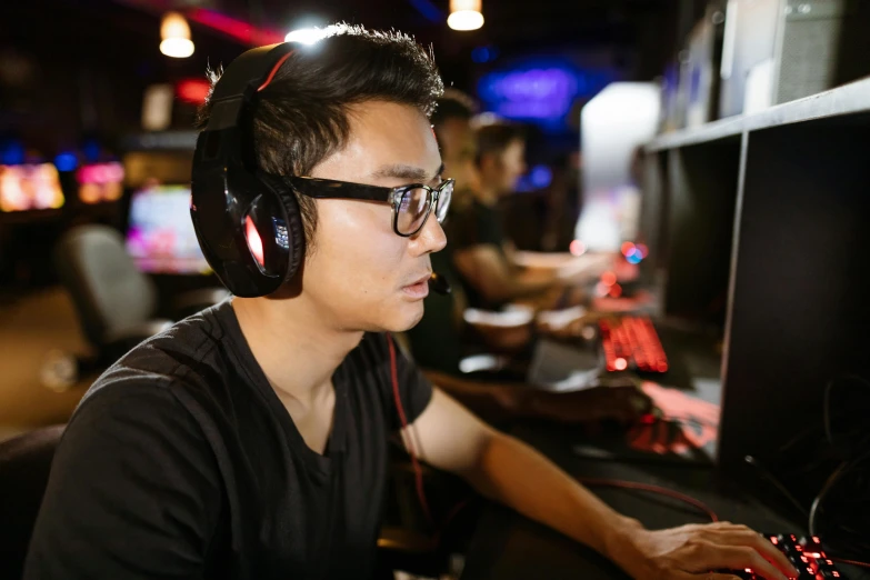 a man wearing headphones sitting in front of a computer, sierra entertainment games, wearing black rimmed glasses, asian male, tournament