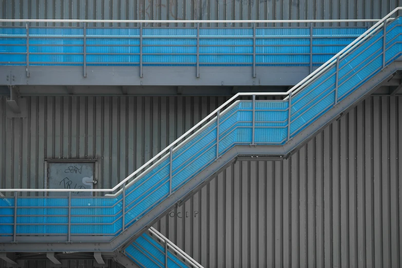 a couple of stairs that are next to a building, unsplash, brutalism, blue metal, industrial colours, shot with sony alpha 1 camera, robert maplethorpe