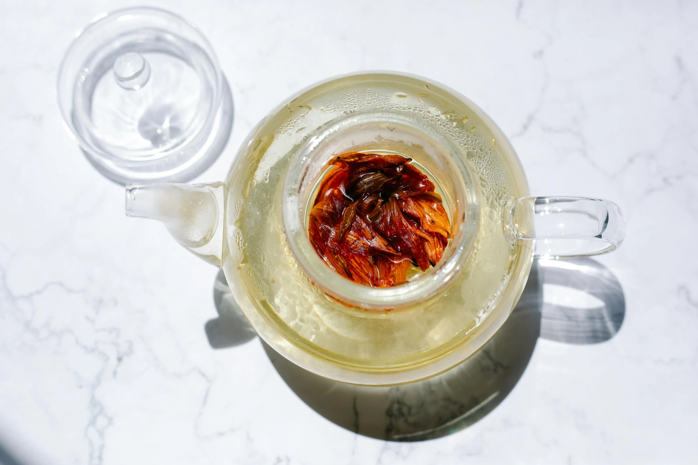 a close up of a glass of water on a table, inspired by Cui Bai, hurufiyya, teapot, flowers inside of a marble, infused, sza