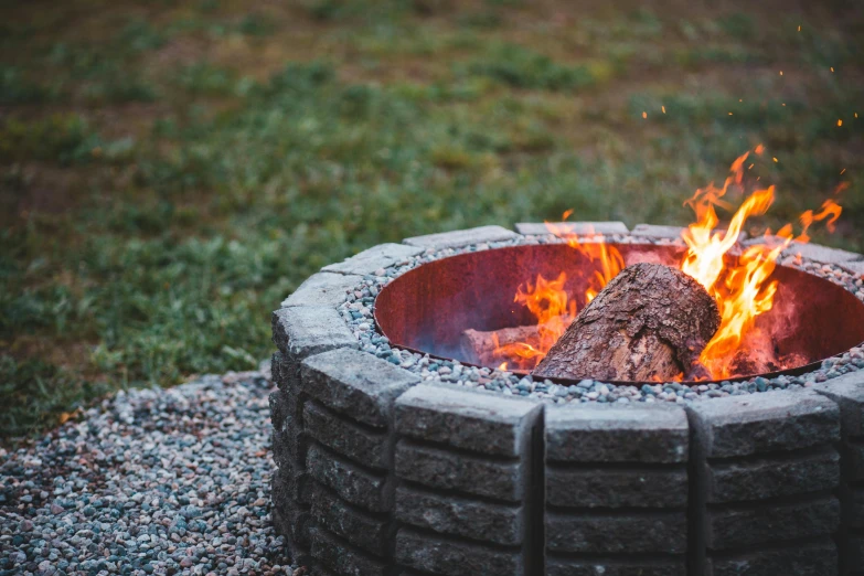 a fire pit sitting on top of a grass covered field, pexels contest winner, gravel, roaring fire, better homes and gardens, gas fire in cracks