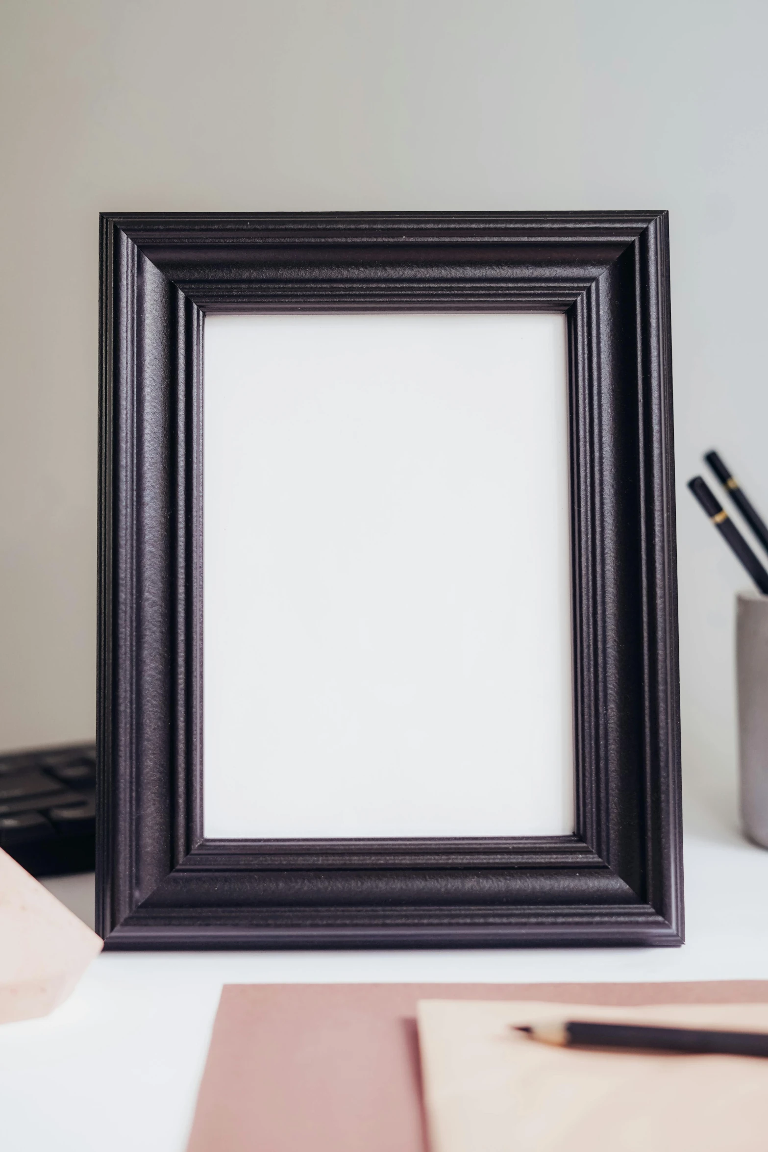 a picture frame sitting on top of a desk, by Joseph Raphael, black matte finish, close up portrait, on a white table, craft