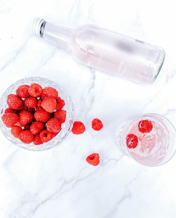 a bowl of raspberries next to a bottle of water, unsplash, sparkling water, white backround, vodka, instagram picture