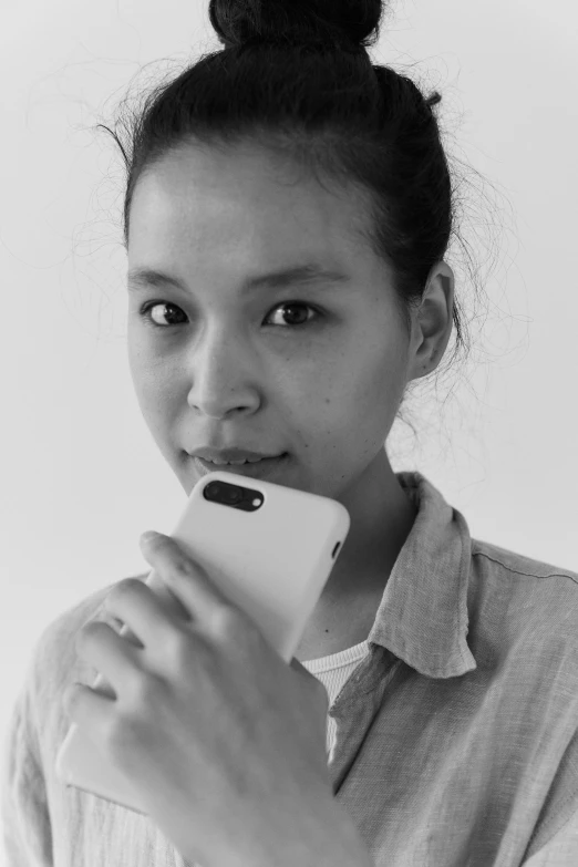 a black and white photo of a woman holding a cell phone, inspired by Cheng Jiasui, nivanh chanthara, half-body portrait, uploaded, [ realistic photography ]