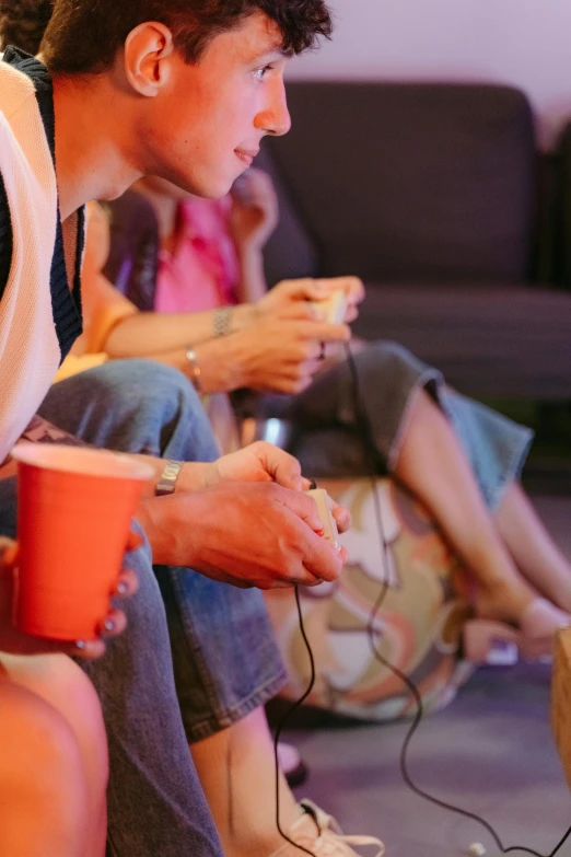 a group of people sitting on a couch playing a video game, by Jan Tengnagel, trending on pexels, interactive art, paper cup, gamecube, hot food, praying