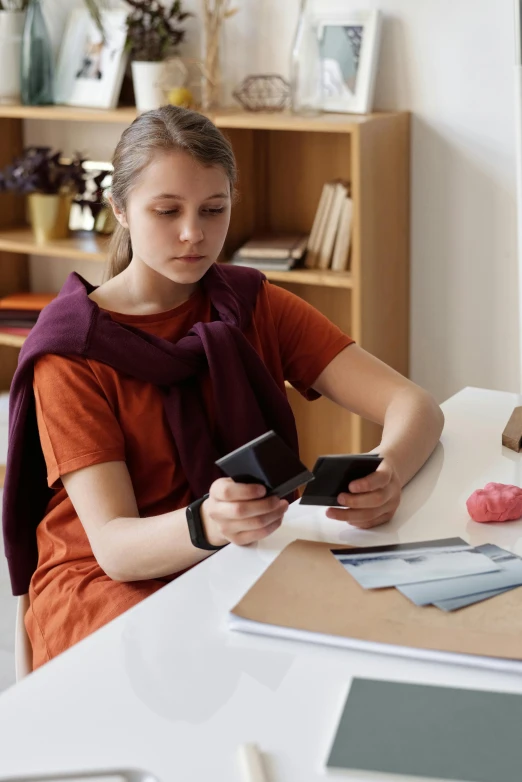 a woman sitting at a table using a cell phone, educational supplies, greta thunberg, holding a leather purse, inspect in inventory image