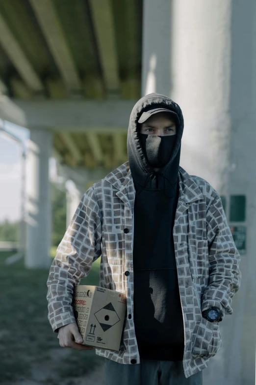 a man with a face mask holding a box, an album cover, unsplash, graffiti, bank robbery movie, patterned clothing, highway, ( ( theatrical ) )