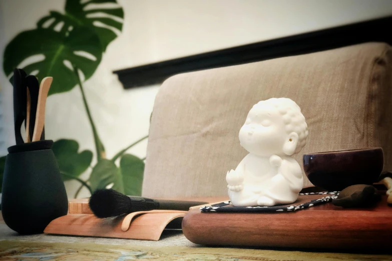 a small figurine sitting on top of a wooden cutting board, a marble sculpture, inspired by Kaigetsudō Ando, unsplash, cherub, holding a boba milky oolong tea, sitting in a lounge, samurai with afro