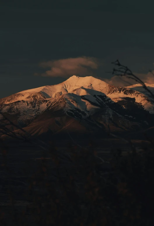 a mountain covered in snow under a cloudy sky, a picture, unsplash contest winner, tonalism, filtered evening light, brown, (night), music video