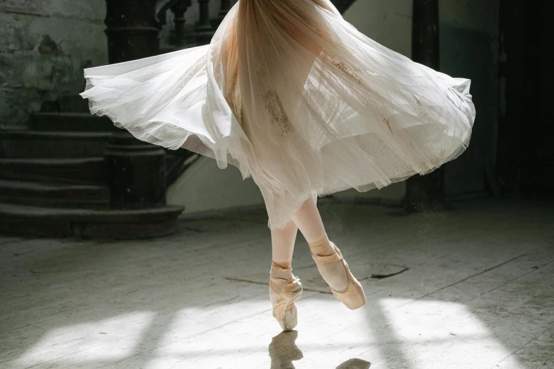 a woman in a white dress is dancing, by Elizabeth Polunin, pexels contest winner, arabesque, airy, [ cinematic, brown, celebrating