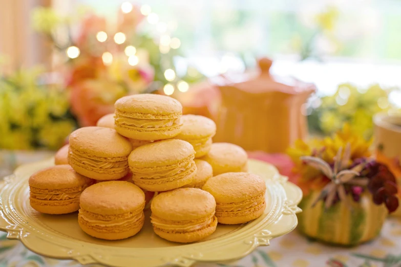 a pile of macarons on a plate on a table, by Alice Mason, pexels, rococo, yellow lanterns, background image