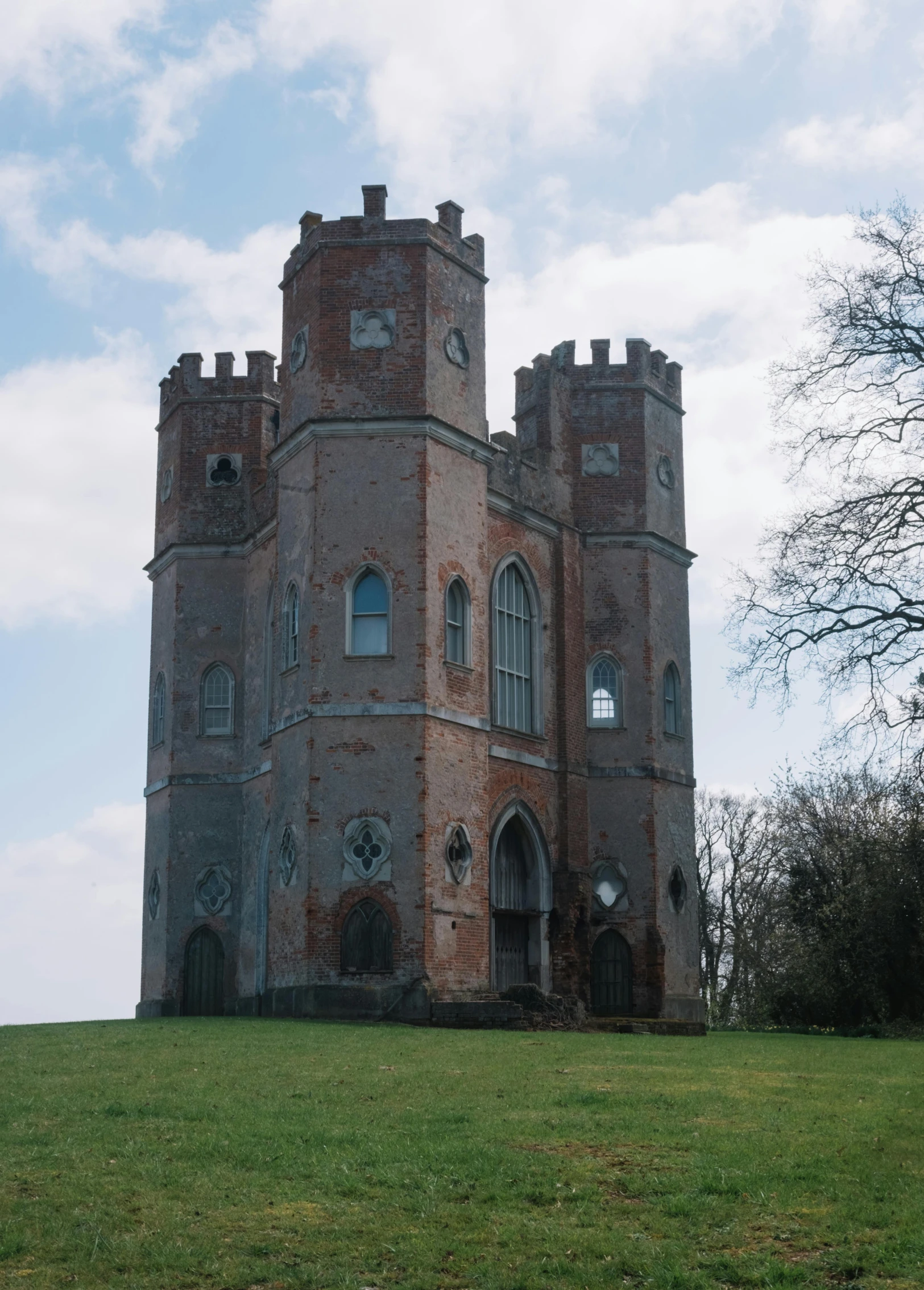 a tall brick building sitting on top of a lush green field, an album cover, inspired by Edmund Leighton, pexels contest winner, renaissance, lookout tower, exterior view, crystal palace, neo-gothic