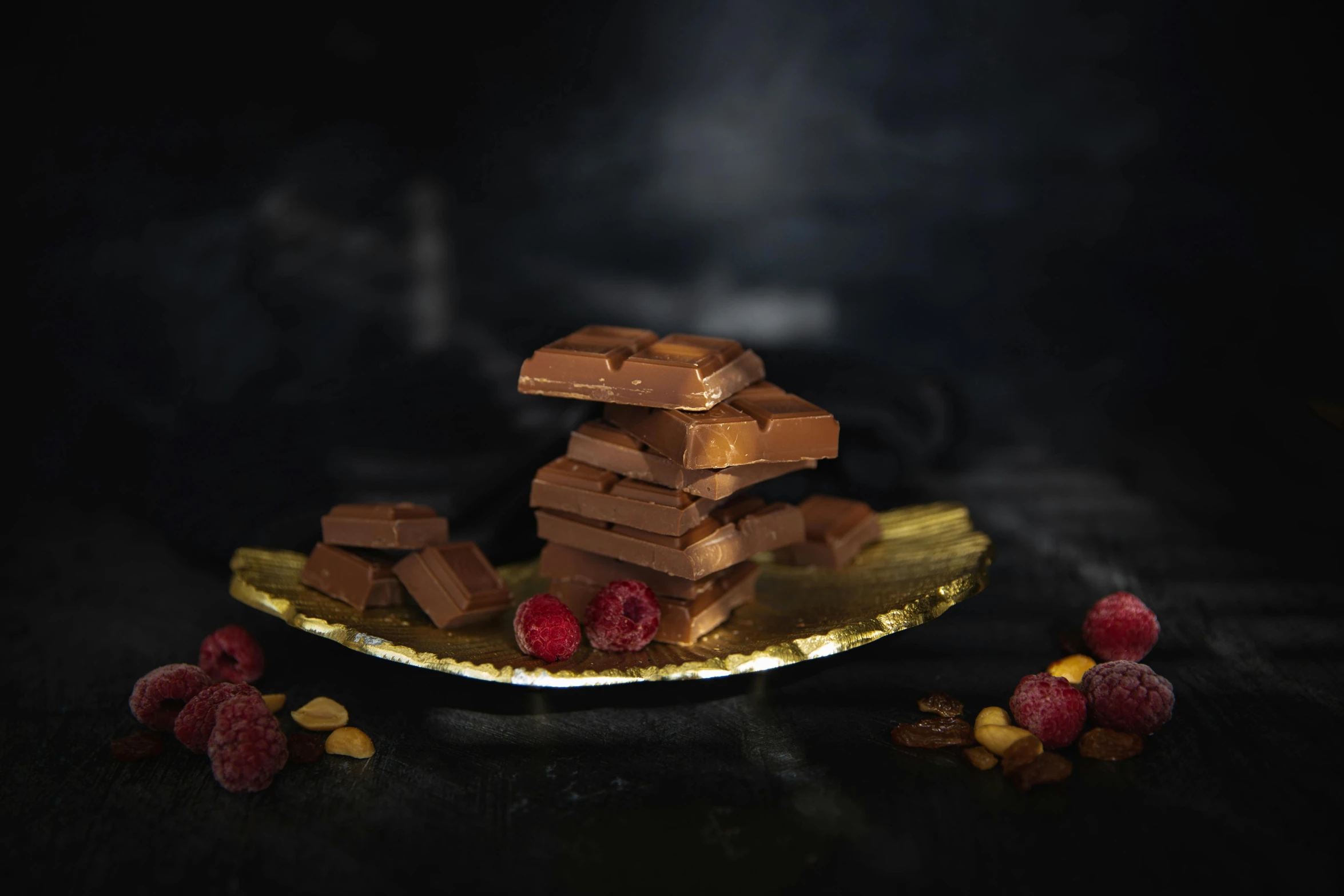 a plate topped with pieces of chocolate and raspberries, a still life, inspired by Jules Robert Auguste, pexels contest winner, product display photograph, stacked, award winning dark, made of polished broze