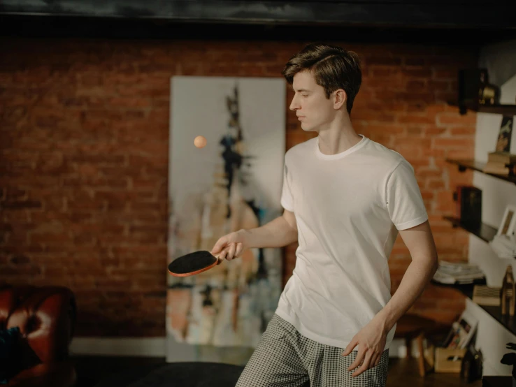 a man holding a ping pong paddle in a living room, by Adam Marczyński, pexels contest winner, renaissance, wearing pants and a t-shirt, performing, gif, white sleeves