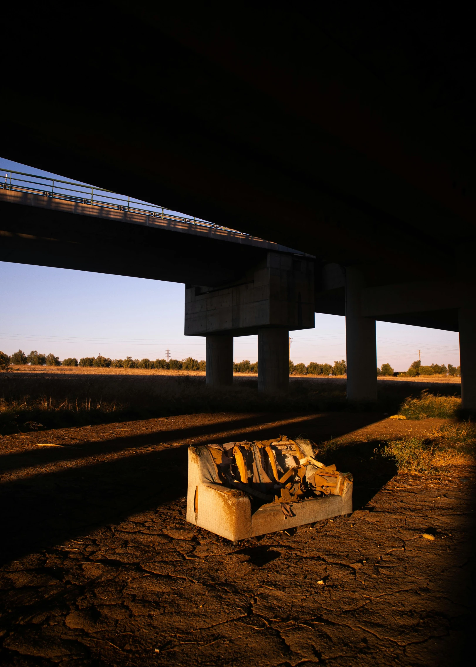 a pile of wood sitting under a bridge, by Brad Holland, conceptual art, couch, sun down, ap news photograph, freeway