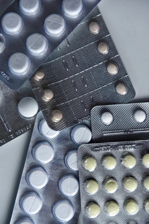 a bunch of contrails sitting on top of a table, a picture, by Paul Davis, plasticien, pills, metallic buttons, grey, product photograph