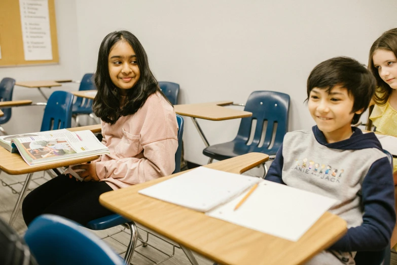 a group of children sitting at desks in a classroom, a portrait, by Carey Morris, pexels contest winner, medium shot of two characters, ayamin kojima, both smiling for the camera, profile image