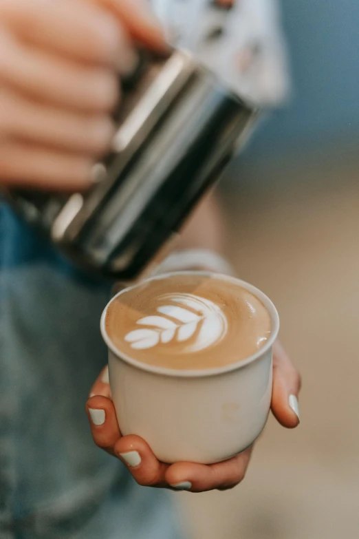 a close up of a person holding a cup of coffee, aussie baristas, coastal, light tan, swirly