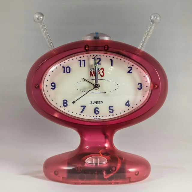 a pink clock sitting on top of a table, inspired by Peter Elson, mtv, antennae, banpresto, red biomechanical details