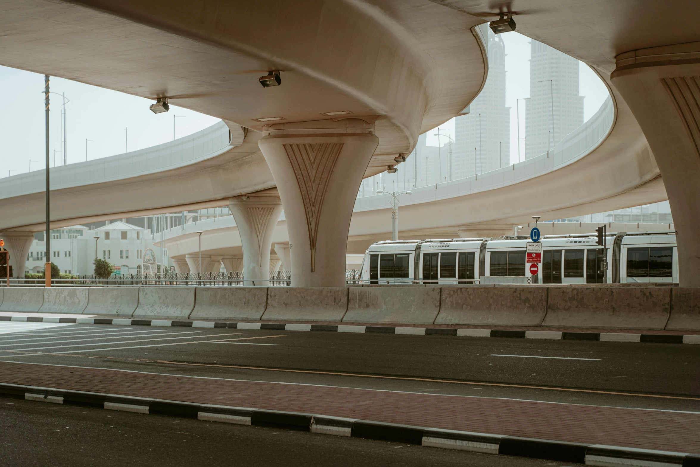 a train passing under an overpass on a city street, inspired by Zaha Hadid, unsplash contest winner, hyperrealism, dubai, buses, 2022 photograph, 1980s photo