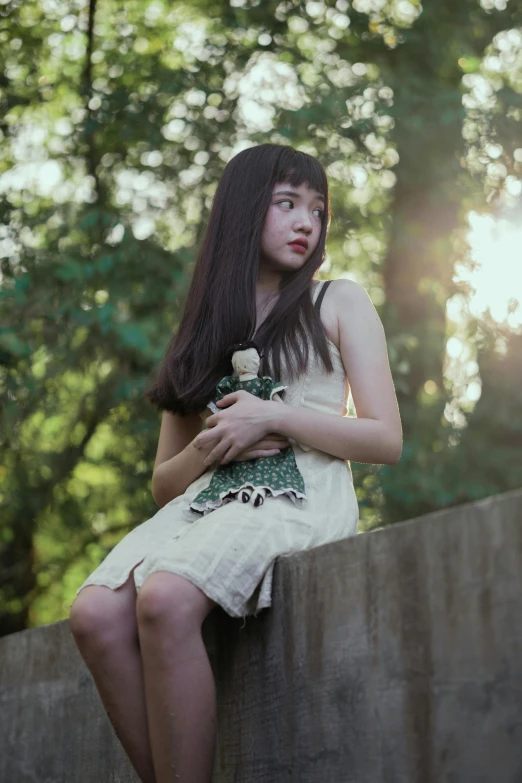 a woman sitting on top of a cement wall, an album cover, inspired by Junji Ito, unsplash, mackenzie foy, wearing a dress made of vines, soft golden hour lighting, ( ( theatrical ) )