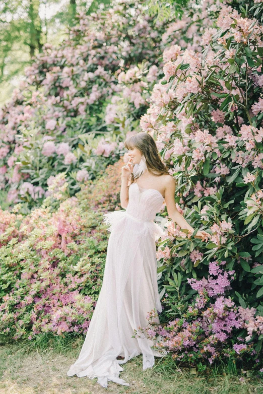 a woman standing in front of a bush of flowers, inspired by Oleg Oprisco, unsplash, wedding, white and pink, may), low quality photo