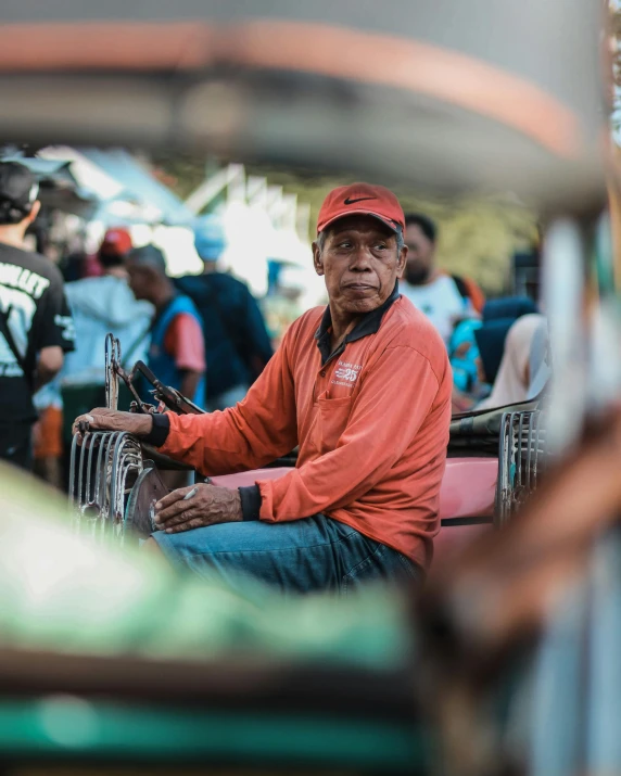 a man sitting on top of a cart next to a crowd of people, pexels contest winner, sumatraism, old charismatic mechanic, profile photo, prideful look, color photo