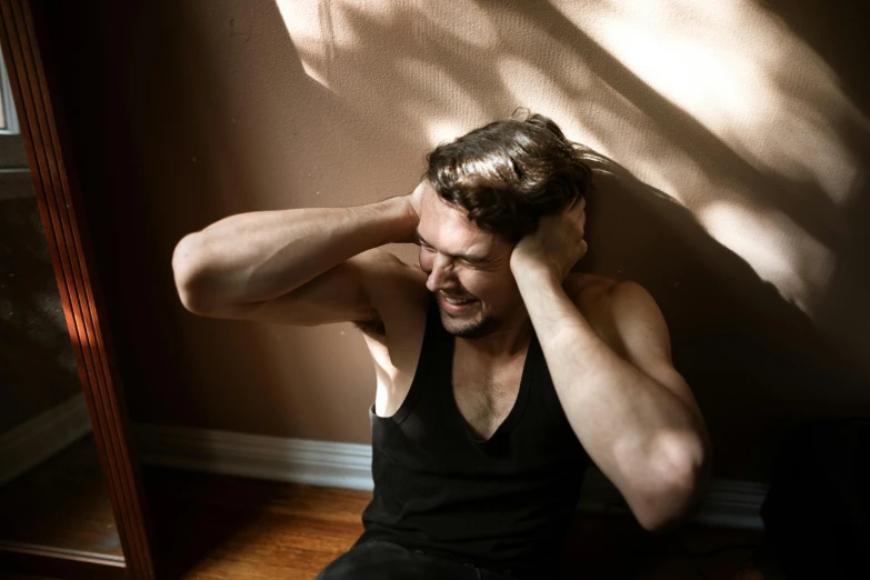 a man sitting on the floor in front of a mirror, harsh overhead sunlight, with his hands in his hair, sweaty face, trending photo