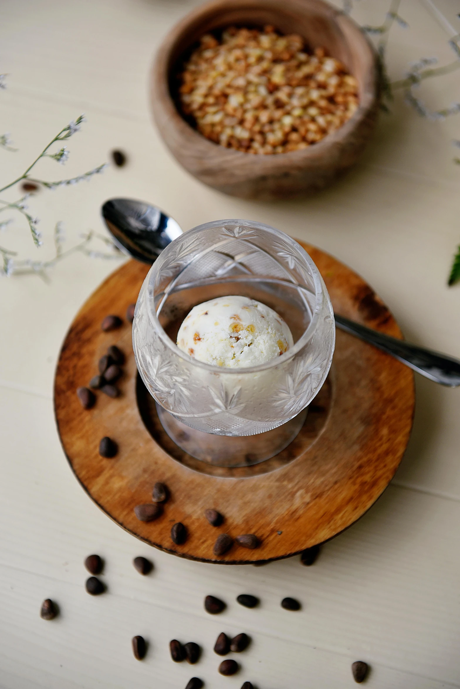 a cup of ice cream sitting on top of a wooden plate, inspired by Ceferí Olivé, renaissance, seeds, white, amber, lifestyle