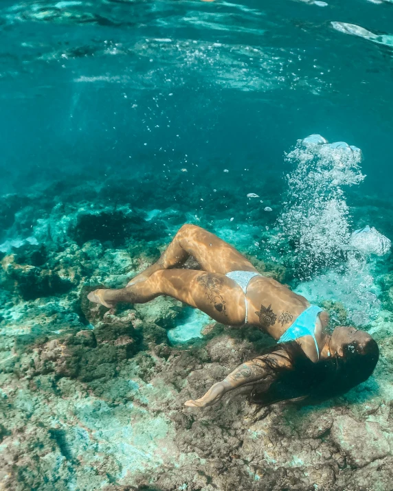 a person swimming in a body of water, reefs, madison beer, at the bottom of the ocean