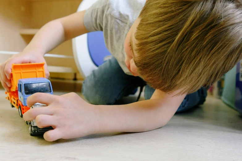 a young boy playing with a toy truck, pexels contest winner, robotic limbs on floor, avatar image, bottom angle, dust and scratches