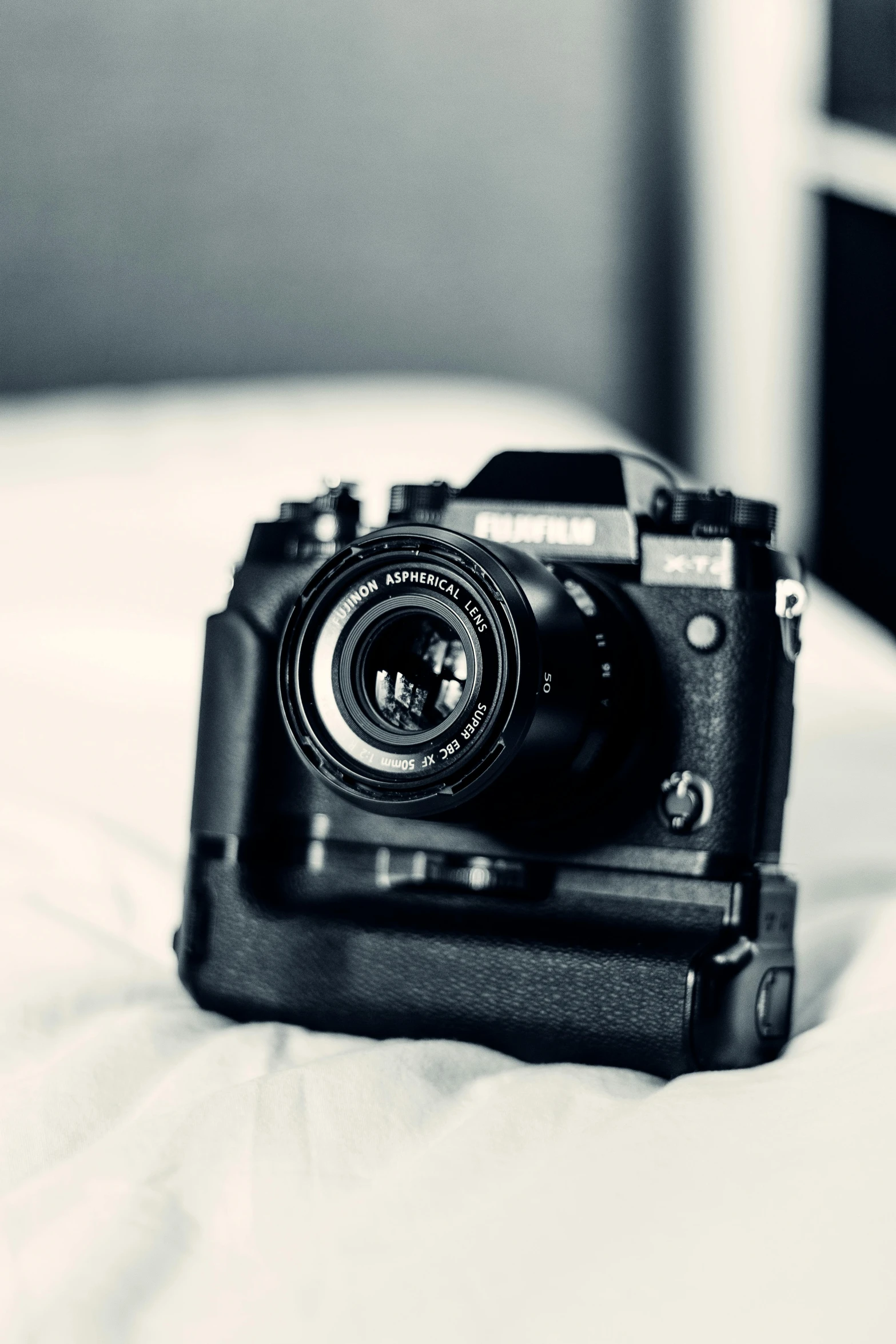 a black and white photo of a camera on a bed, inspired by Elsa Bleda, unsplash, medium format. soft light, colored photography, fujifilm x-t3, with laser-like focus