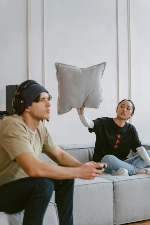 a couple of people that are sitting on a couch, wearing a headset, throw pillows, in a room, air shot