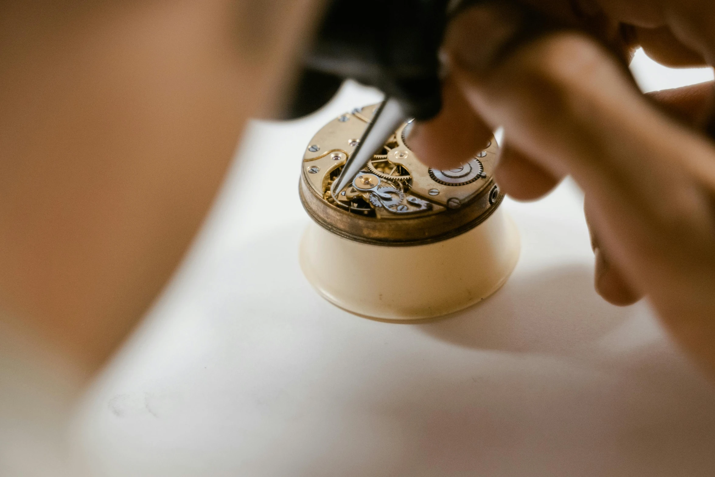a close up of a person working on a watch, an engraving, trending on pexels, process art, capacitors and coils inside, faberge, on a white table, warm shading