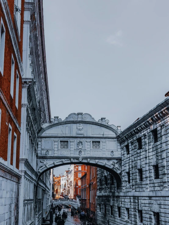 a couple of people walking down a street under a bridge, pexels contest winner, renaissance, indigo! and venetian red!, white marble buildings, thumbnail, medieval gates