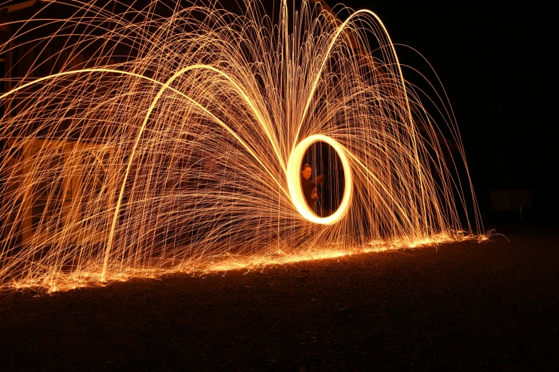 a person standing in front of a ring of fire, a stipple, by Jan Rustem, pexels contest winner, some chaotic sparkles, brown, long exposure 8 k, outside intricate