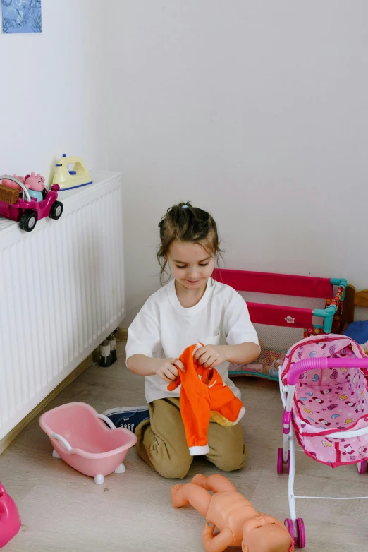 a little girl sitting on the floor playing with toys, by Julia Pishtar, pexels contest winner, laundry hanging, wearing an orange t-shirt, gif, girl wearing uniform